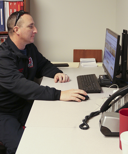 Firefighter sitting at a desk looking at his computer